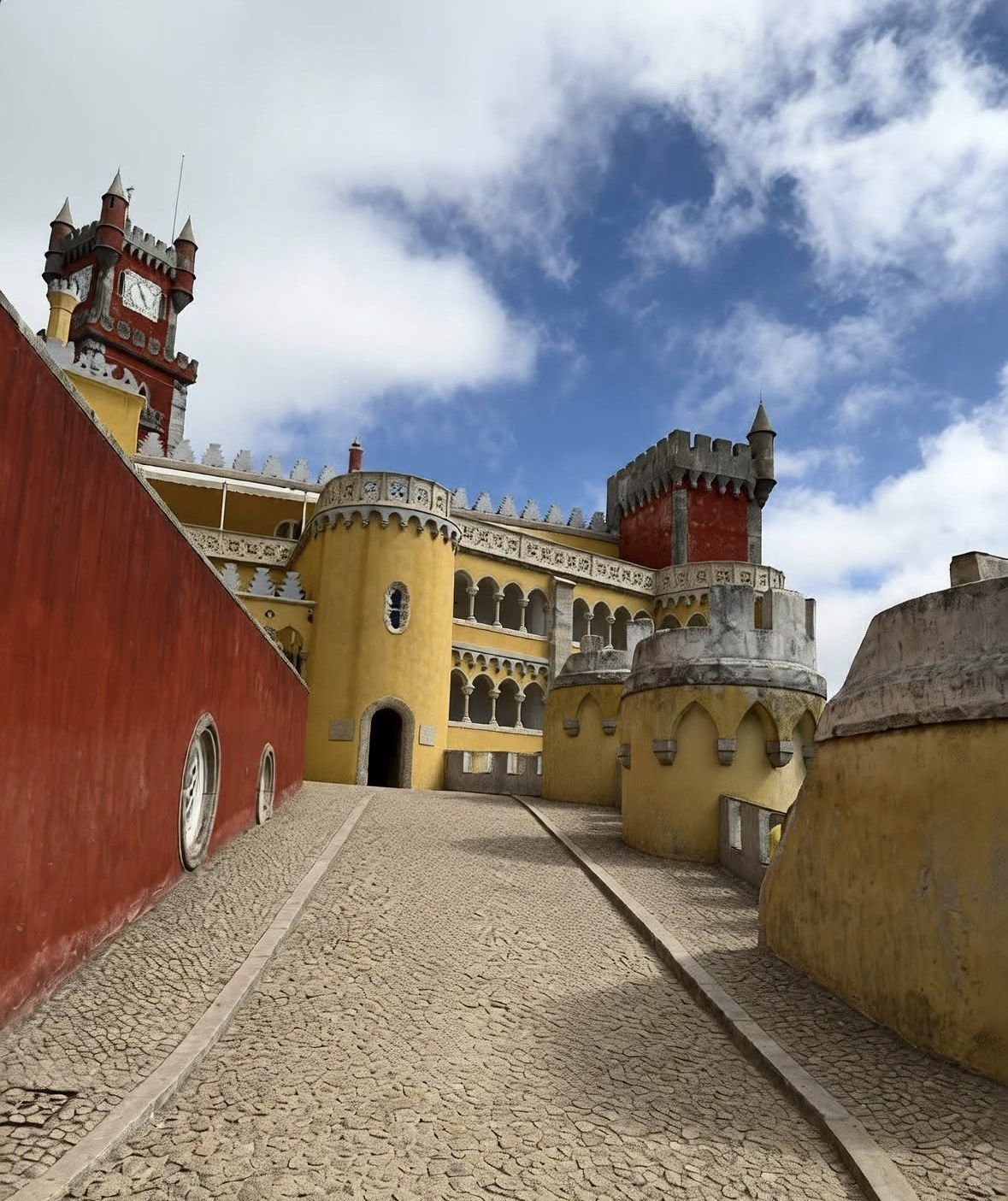 Cobbled rampart path between red wall and yellow Pena Palace towers