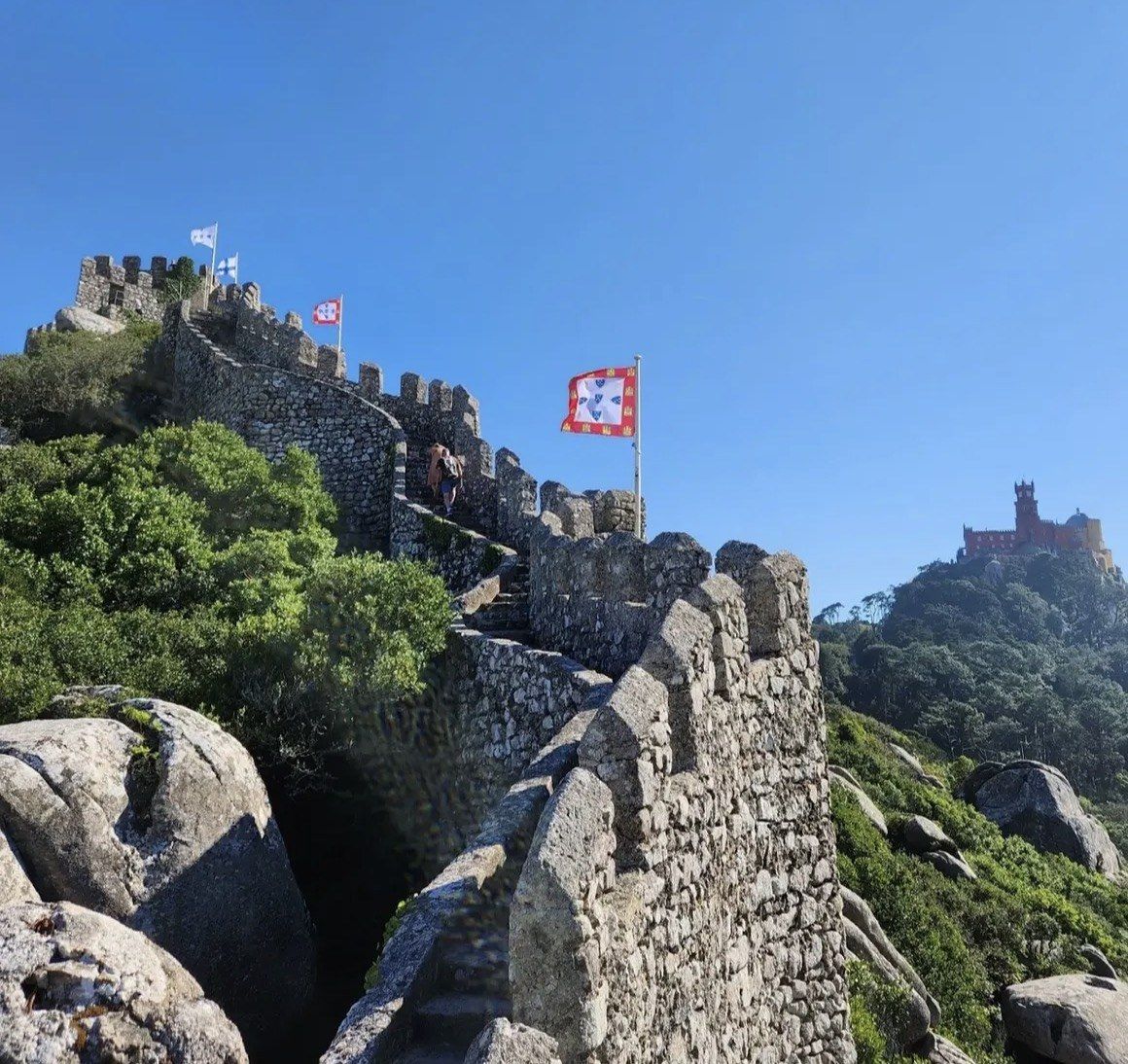 Royal banners on Moorish Castle walls with Pena Palace on the far hill