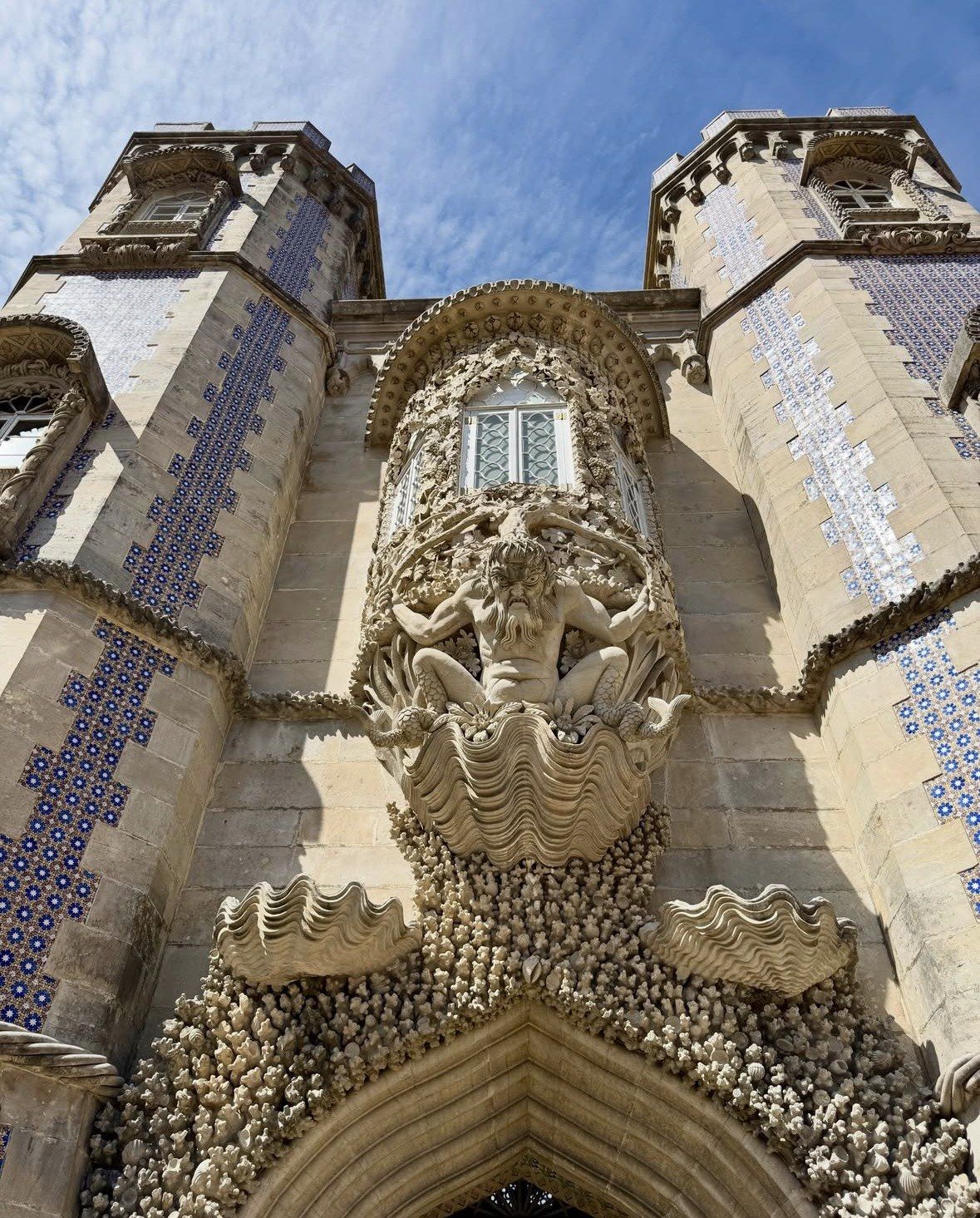 Triton carving and tiled towers seen from below at Pena Palace